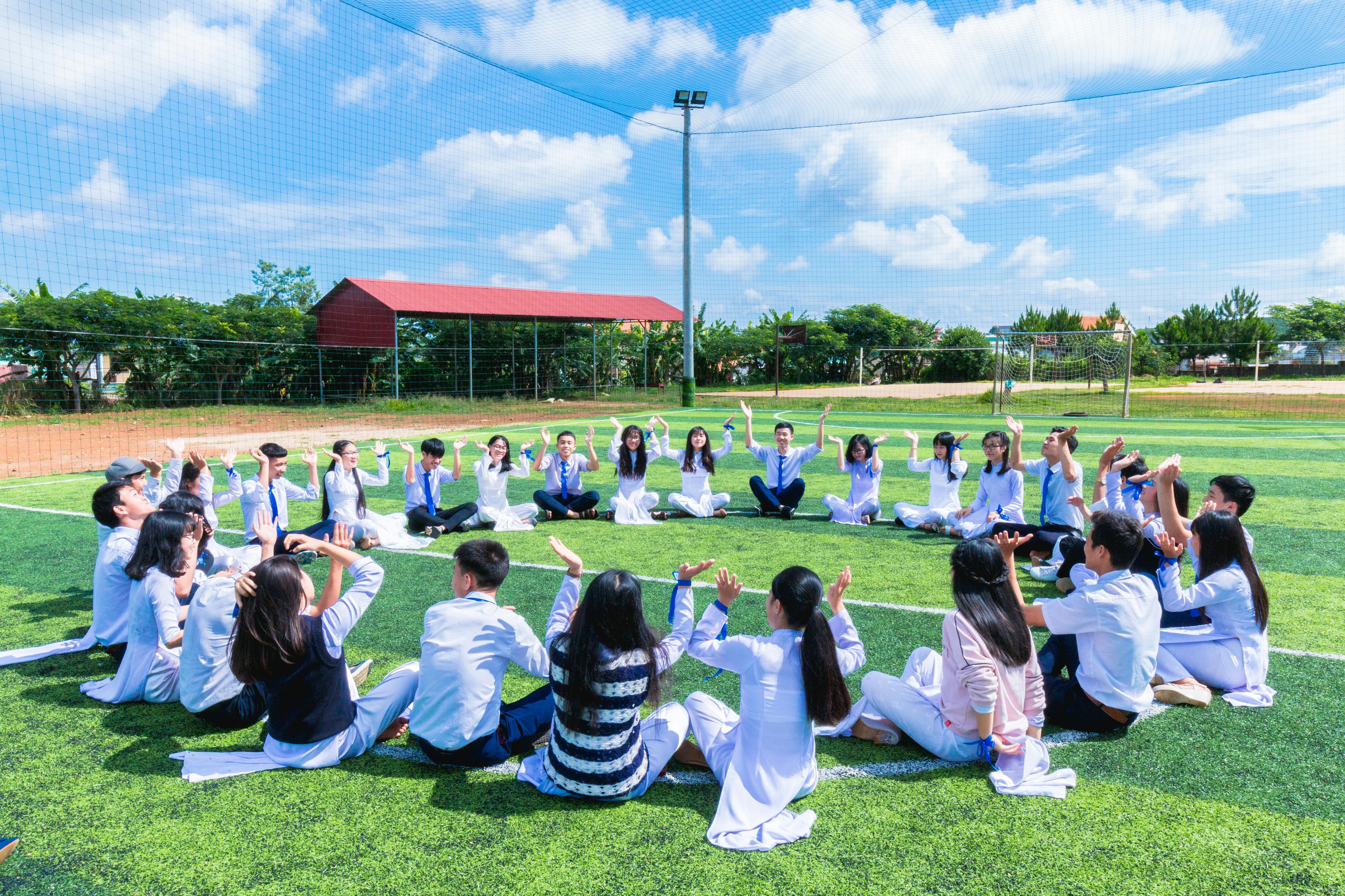 Students sitting in a circle in the center of a green field